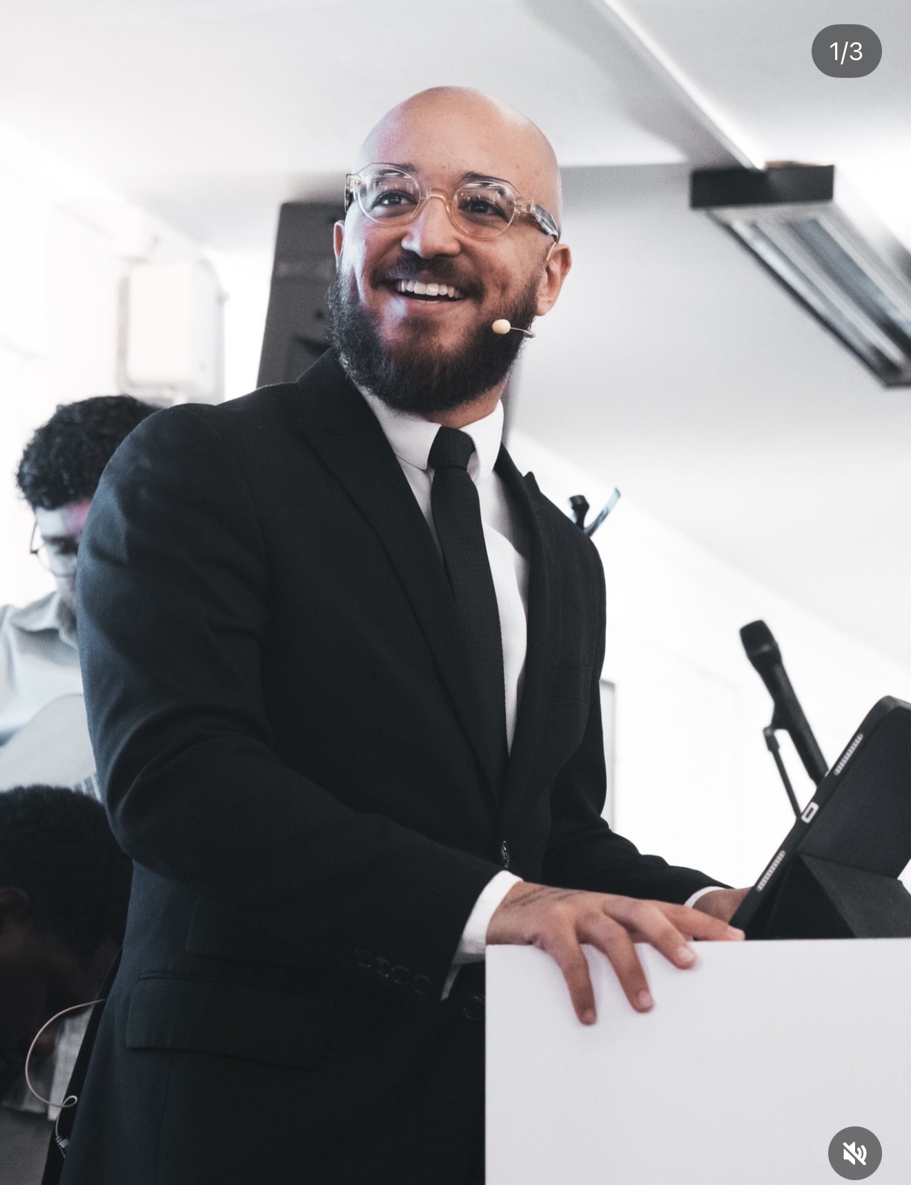 Caio Escovino sorrindo enquanto conduz uma apresentação com microfone headset.